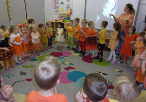 dzieci ubrane na pomarańczowo tańczą według instrukcji