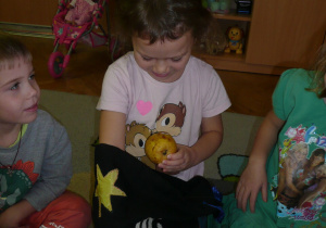 dziewczynka rozpoznaje po dotyku owoc