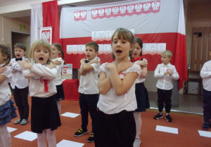Juniorzy śpiewają piosenkę na tle dekoracji z okazji Dnia Niepodległości