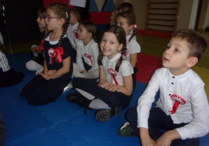 dzieci w galowych strojach oglądają występy konkursowe