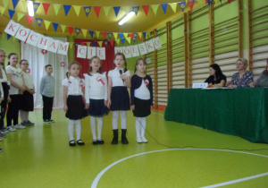 cztery dziewczynki w galowych strojach śpiewają piosenkę