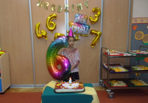 sześcioletnia Solenizantka na tle dekoracji Urodzinkowej