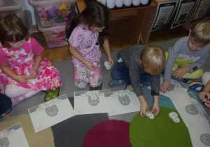 dzieci układają obrazki na dywanie
