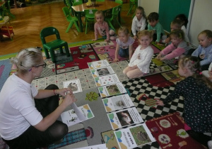 Tuptusie siedzą na dywanie i odpowiadają na pytania nauczyciela