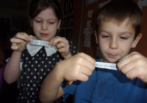 dwoje dzieci odczytuje wróżbę zapisaną na karteczkach