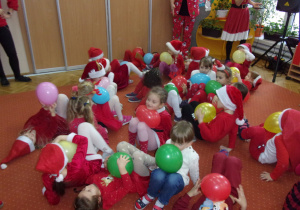 dzieci ubrane na czerwono w mikołajkowych czapeczkach podczas zabawy z balonami