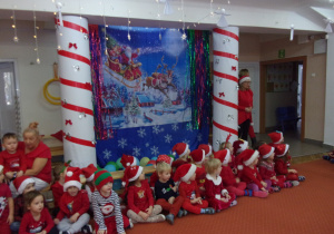 dzieci siedzą na sali gimnastycznej w oczekiwaniu na Mikołaja