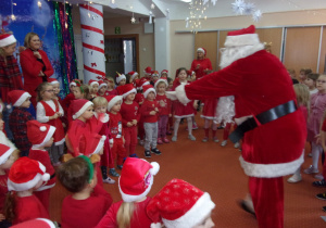 Mikołaj tańczy z dziećmi ubranymi na czerwono