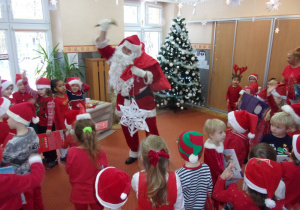 Mikołaj tańczy z dziećmi ubranymi na czerwono