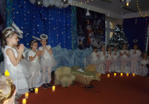 dziewczynki w strojach aniołków na tle dekoiracji świątecznej