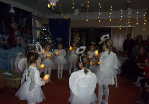 dziewczynki ze światełkami w strojach aniołków stoją w kole