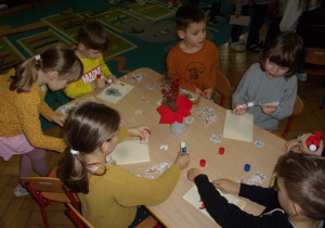 Żaczki i Juniorzy przy stolikach podczas wykonywania kartki świątecznej