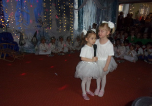 dwie dziewczynki w białych spódniczkach i białych kwiatuszkach na gumkach do włosów