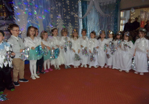 dzieci śnieżynki śpiewają piosenkę na tle dekoracji do bajki "Królowa Śniegu"