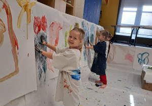dzieci malują rękoma farbami na białym papierze