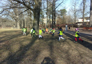 Juniorzy biegają między drzewami w parku