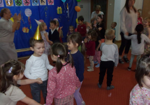 wspólny taniec dzieci ze wszytkich grup na sali gimnastycznej, w tle dekoracja urodzinkowa