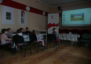 Juniorzy oglądają film na tablicy interaktywnej w Muzeum Tradycji Niepodległościowych