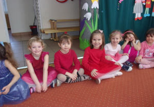 dziewczynki siedzą na dywanie na sali gimnastyczej