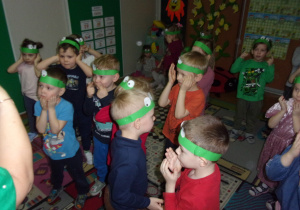 zabawa ruchowa na dywanie - dzieci z opaskami żabek na głowach